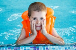 Child in life jacket posing in swimming pool 