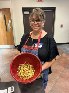 woman smiling while wearing an apron and holding a bowl